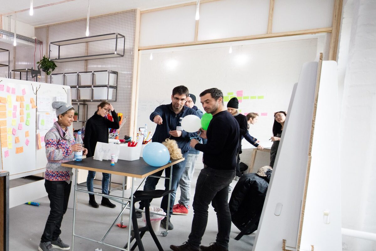 Teilnehmende arbeiten in Kleingruppen an Stehtischen und Whiteboards im White Space von Dark Horse