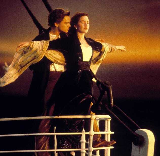 Jack und Rose an der Bugreling der Titanic mit ausgebreiteten Armen vor Abendhimmel – der Moment kurz vor der Kollision mit dem Eisberg